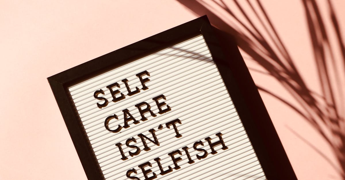 Letter board displaying 'Self Care Isn't Selfish' with artistic shadow on pink background.