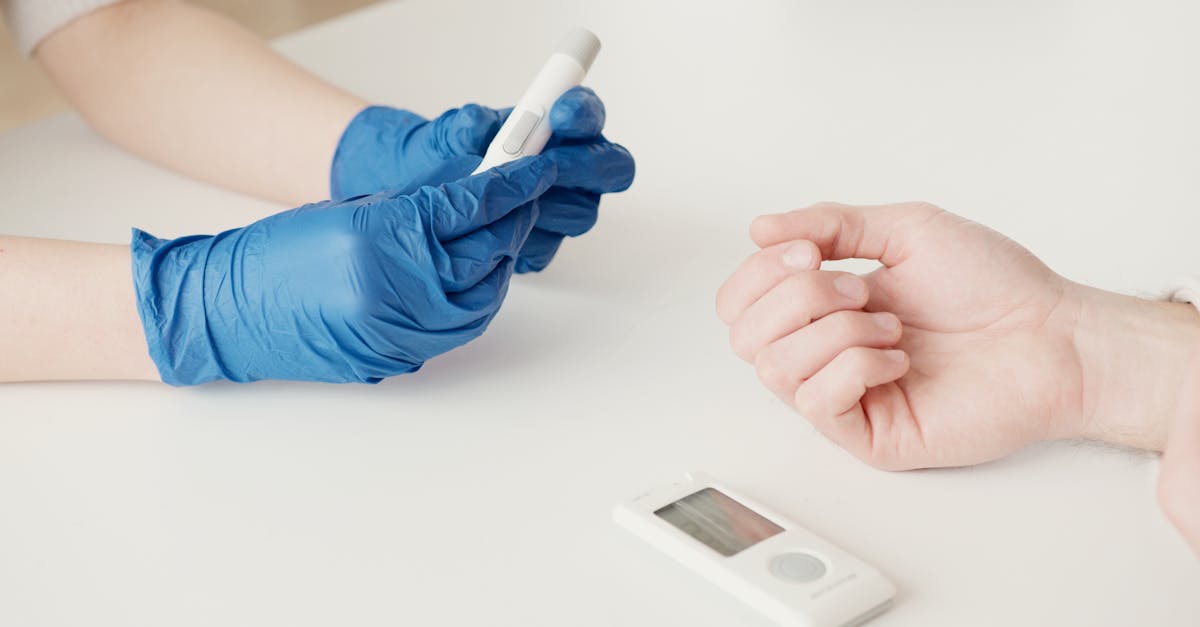 A healthcare worker uses a glucometer to check blood sugar levels in an indoor setting.