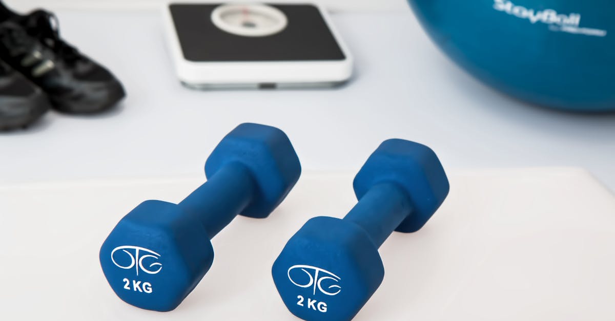 Blue dumbbells placed on a white surface with fitness equipment in the background.